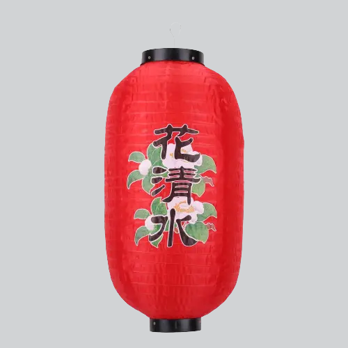 Lanterne japonaise en papier rouge avec bordure noire et caractères chinois entourés de feuilles vertes.