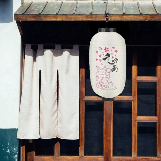 Lanterne japonaise en papier avec fleurs de cerisier et décorations calligraphiées.