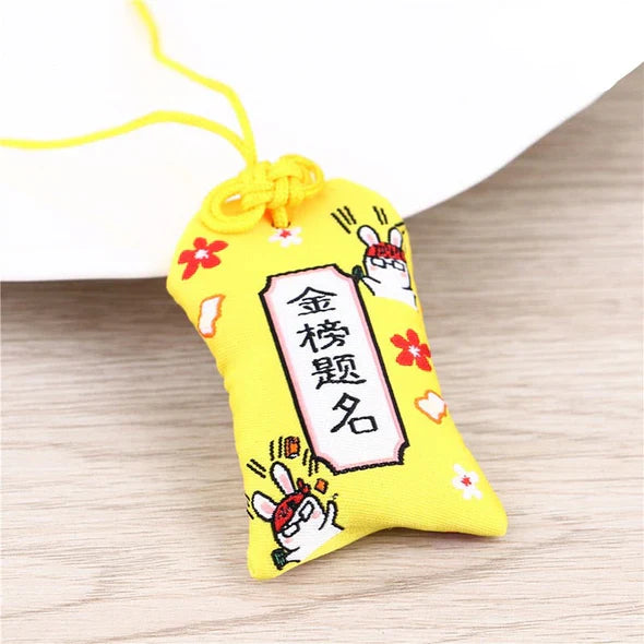 Breloque ou amulette en tissu jaune avec des caractères chinois et des décorations en forme de lapin.