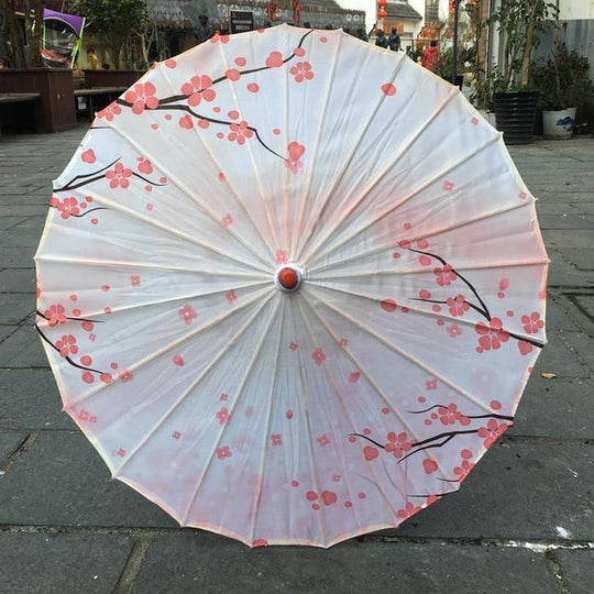 Parasol en papier blanc décoré de fleurs de cerisier roses.