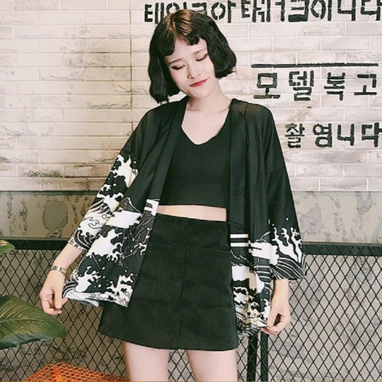 Un cardigan de style kimono à fleurs noires et blanches porté avec un ensemble crop top et jupe assortis.