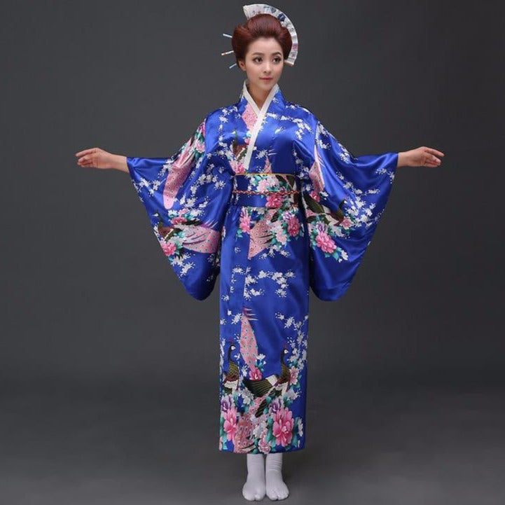 Kimono japonais traditionnel bleu royal avec des motifs floraux roses et de larges manches fluides.