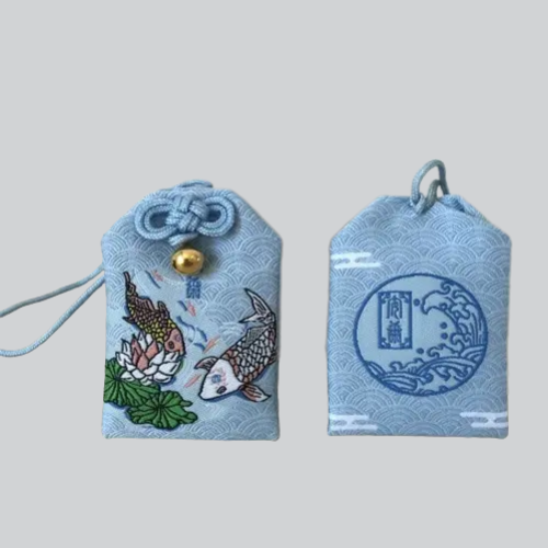 Amulette japonaise omamori avec des motifs de poissons koï et de fleurs de lotus dans un tissu bleu clair.