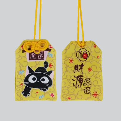 Breloque omamori de style japonais avec un chat noir sur fond jaune.