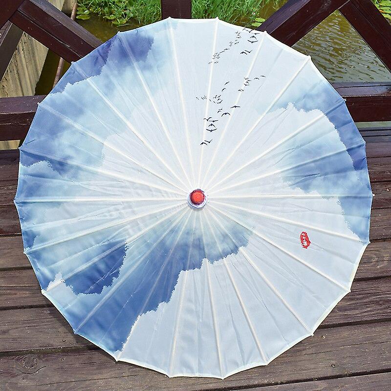 Parasol traditionnel en papier avec un motif de ciel bleu et de nuages peint sur un tissu blanc.