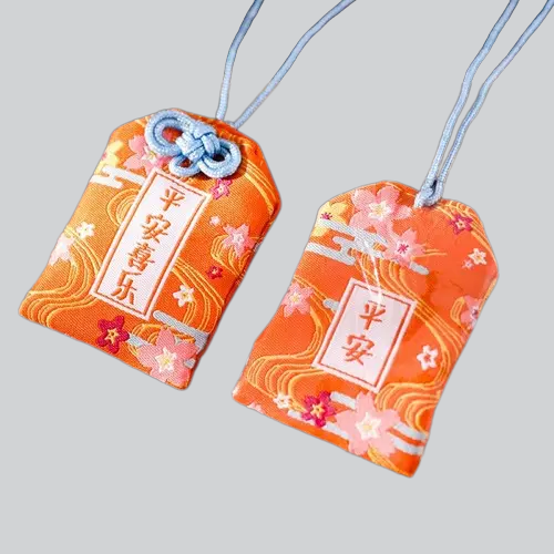 Pochettes japonaises orange omamori (porte-bonheur) avec motifs floraux et caractères kanji.