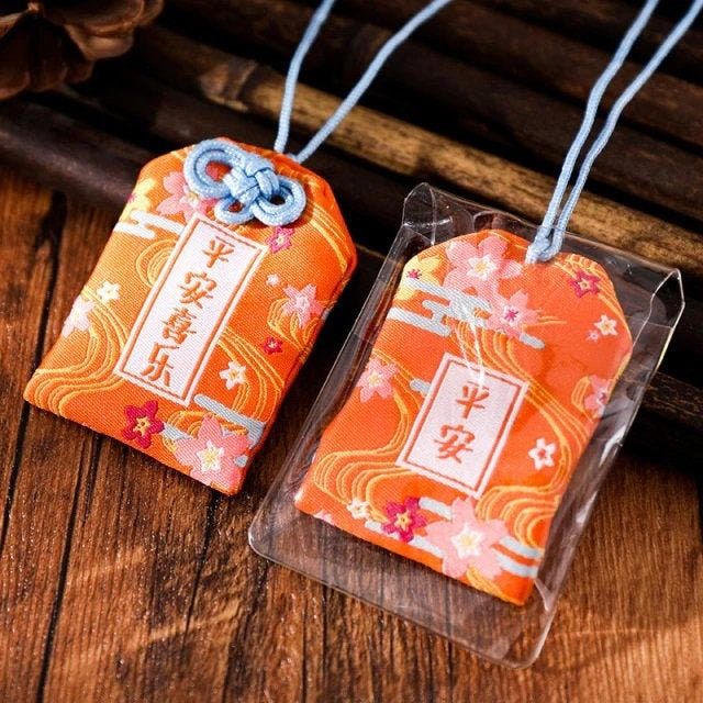 Pochettes japonaises orange omamori (porte-bonheur) avec motifs floraux et caractères chinois.