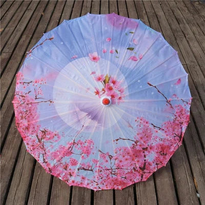 Parasol traditionnel japonais en papier décoré de fleurs de cerisier roses sur fond de ciel lavande.