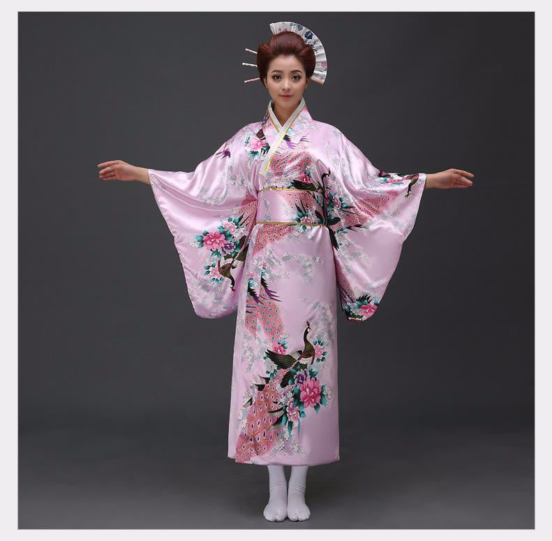 Kimono rose à fleurs avec de larges manches fluides et des ornements de cheveux japonais traditionnels.